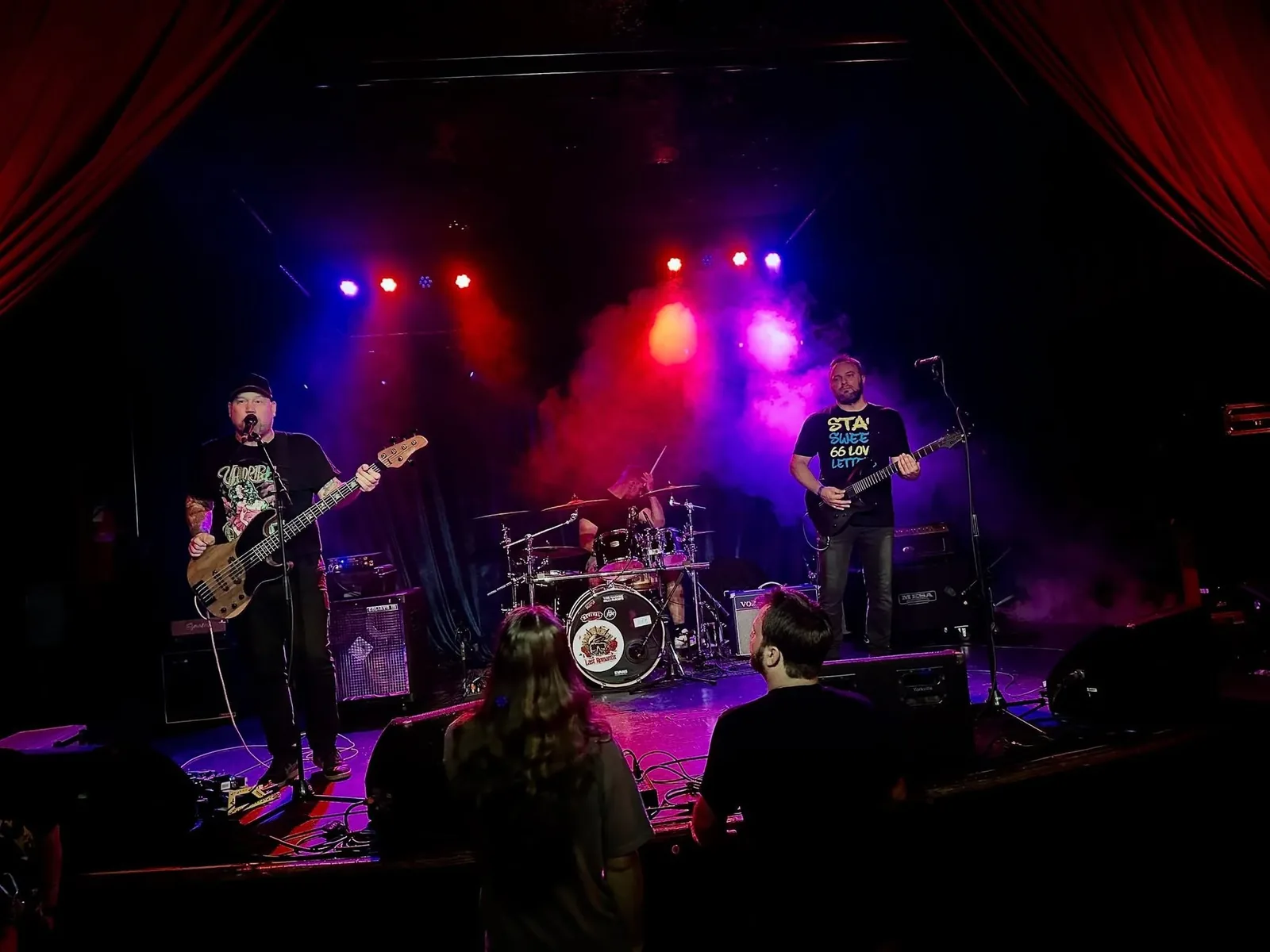 CARD3N on stage under magenta and blue lights and haze, mid-song